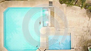 Drone view swimming pool in tropical resort hotel. Young man diving in blue water swimming pool while summer vacation in