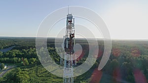 Drone view at telecommunication tower, worker servicing cellular antenna