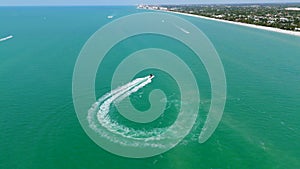Drone view of turquoise waters of Naples, Florida. Motor boat making sharp turn and leaving behind white foamy trail