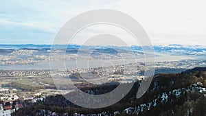 Drone view from Uetliberg tower with view to lake Zurich and mountain range at hazy late afternoon in wintertime