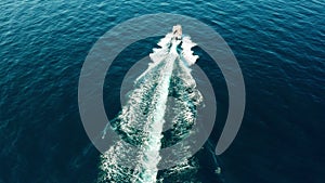 Drone view of a white boat sailing in the blue sea. A white yacht moving at high speed.