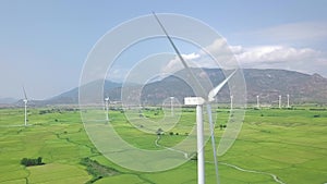 Drone view wind power station in green field on mountain landscape. Windmill turbine, generating wind power aerial view