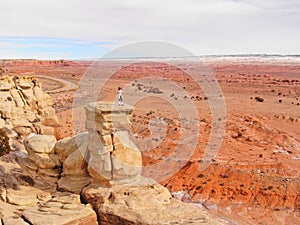 DRONE: Woman standing on top of a sandstone formation taking photos of canyon