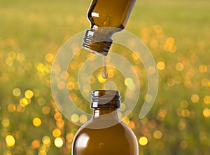 A drop of aromatherapy oil falls from the top into a brown bottle.