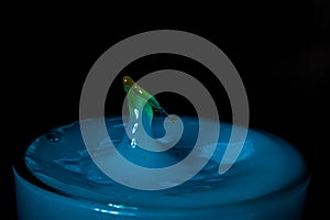 Drop of beer in glas with blue liquid