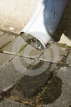 A drop of clean rain water flows down a old drainpipe sunny weather after rain