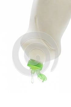 A drop of dishwashing gel flows out of the bottle. The layout is made of white plastic with gel for washing dishes.