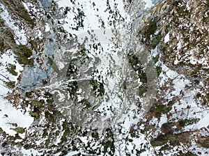 Drop down view of a mountain river flowing through winter forest.