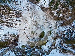 Drop down view of a mountain river flowing through winter forest.