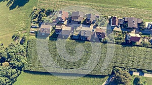 Drop down view of rural houses next to corn field.