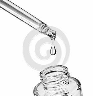 Drop falls from a pipette into a cosmetic bottle on white photo
