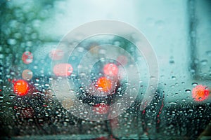 Drop on glass at twilight time while raining.View side out the car.Rain drops on window with road light bokeh,