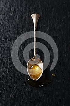 Drop of honey in a silver spoon
