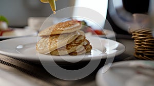 A drop of honey spreads over the pancake. Pancakes with syrup macro shot. Syrup pours onto a macro photo of a pancake. A