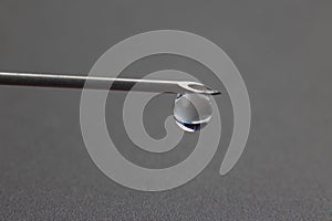 Drop of liquid hangs on the tip of a medical injection needle