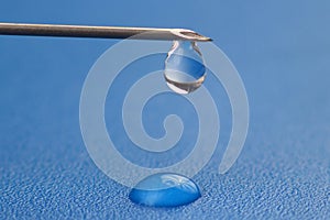 Drop of liquid hangs on the tip of a medical injection needle