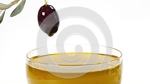 A drop of olive oil falling from one black olive