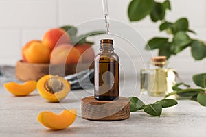 A drop of skin care serum is dripping from a pipette into a bottle. Oil with apricot kernel extract to nourish the skin