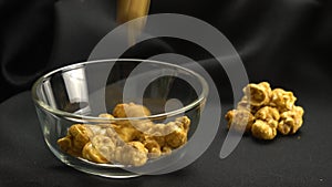 Drop sweet caramel almonds into transparent glass bowl.