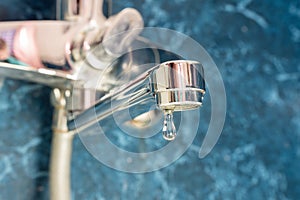 A drop of water drips from a leaky faucet