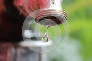 A drop of water leaking from the faucet