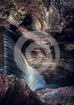 drop of waterfall in canyon narrow and dark background vertical gorge