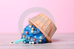 Dropped cupcake with cream on white wooden table, closeup. Troubles happen