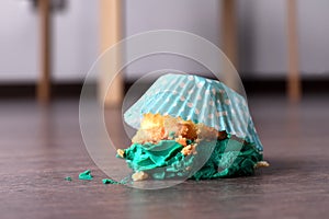 Dropped cupcake with cream on wooden floor at home, closeup. Troubles happen