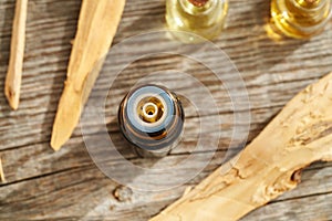 A dropper bottle of essential oil with white sandalwood pieces