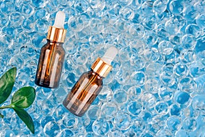 Dropper bottles of facial anti aging serum with collagen and peptides on blue gel bubbles background with copy space