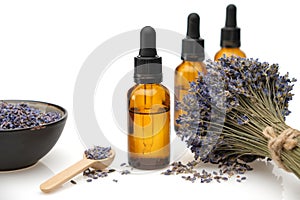 Dropper bottles of lavender essential oil or aromatic flower water and bunch of dried lavender flowers on white