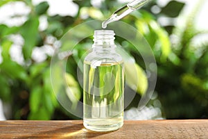 Dropper with essential oil  bottle on wooden table against blurred background