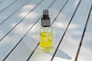 Dropper glass Bottle Mock-Up. Cosmetic pipette serum on white wooden background with shdows and hard light photo