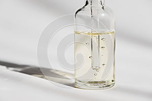 Dropper glass Bottle Mock-Up. Cosmetic pipette on white background. Oil bubbles. photo
