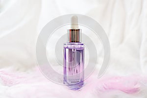 Dropper glass bottle with pipette. Mock up Essential liquid . On white background with pink feathers