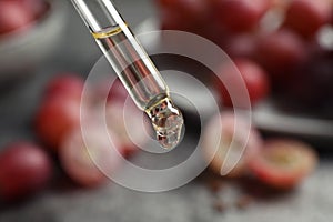 Dropper with natural grape seed oil on background, closeup. Organic cosmetic