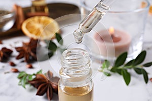 Dropping anise essential oil from pipette into bottle on table, closeup