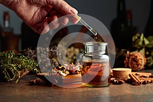 Dropping essential herbal tincture into a small glass bottle