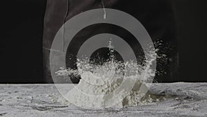 Dropping fresh yolk into heap of flour on a black background. Step by step preparing nature dough for homemade pasta