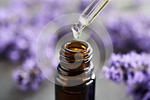 Dropping lavender essential oil into a brown glass bottle