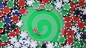 Dropping red dice on a green table with poker chips in slowmo filmed from above
