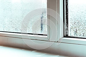 Drops of condensate and black mold on a white plastic window