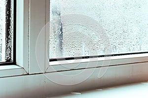 Drops of condensate and black mold on a white plastic window