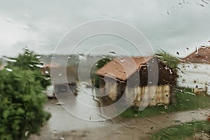 Drops on glass in rainy day. Rain outside window in autumn day. Texture of raindrops, wet glass. Rainy window background.Rural