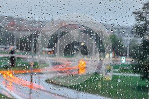 Drops on glass in rainy day. Rain outside window in the town. Texture of raindrops, wet glass. Rainy window background