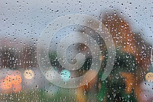 Drops on glass in rainy day. Rain outside window in the town. Texture of raindrops, wet glass. Rainy window background.City