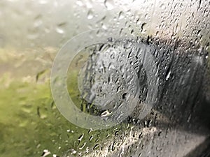 Drops of rain on the car window & x28;glass& x29; with a view of the exterior mirror and blurred background