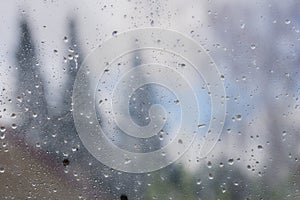 Drops of rain and condensation on the window, blurred trees in the background