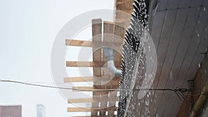 Drops of rain fall from the roof of the pavilion, raindrops flow down, close-up