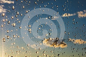 Drops of rain shining on a window glass blue sky in background